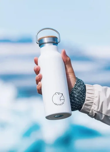 Branded Arcticus insulated bottle in a hand with Arctatica backdrop
