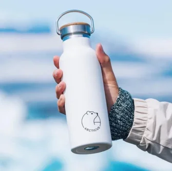 Branded Arcticus insulated bottle in a hand with Arctatica backdrop
