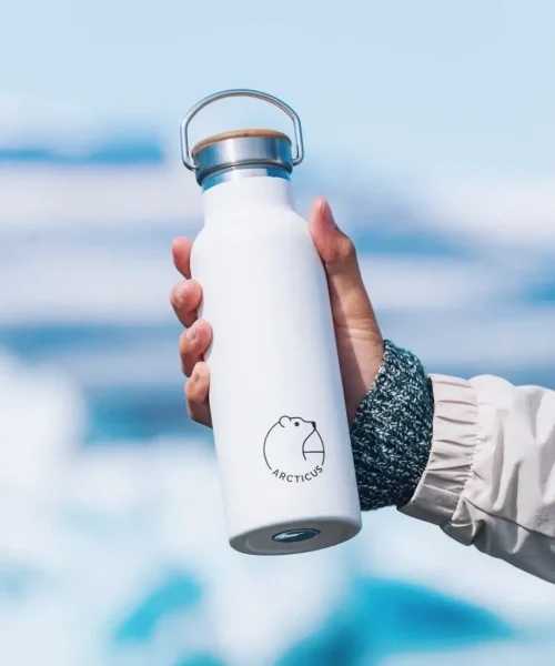 Branded Arcticus insulated bottle in a hand with Arctatica backdrop